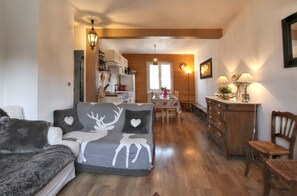Un soggiorno accogliente con un divano, un tavolo da pranzo in legno e una zona cucina sullo sfondo.
