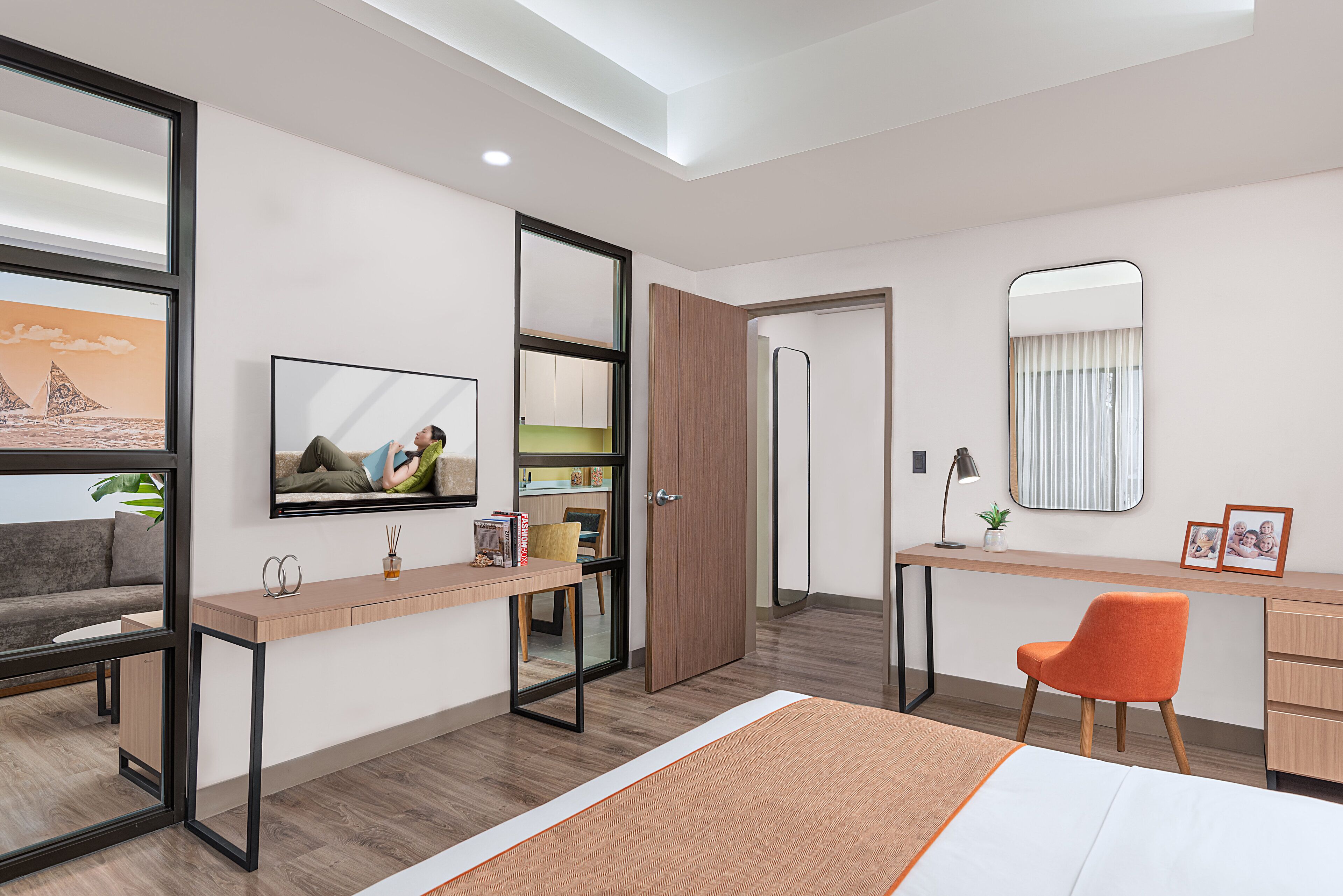 A modern hotel room with a bed, a desk, a chair, a TV, and a wardrobe.