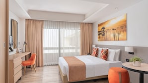 A hotel room with a bed, a desk, a chair, a round table, and a painting on the wall. - Citadines Amigo Iloilo (Iloilo)