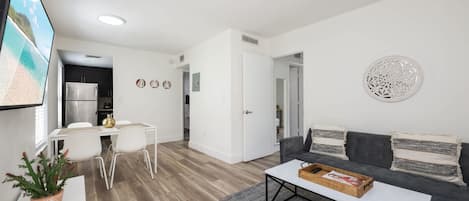 A modern living room with a sofa, coffee table, and a dining area with chairs.