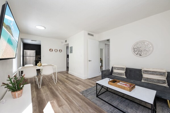 A modern living room with a sofa, coffee table, and a dining area with chairs.