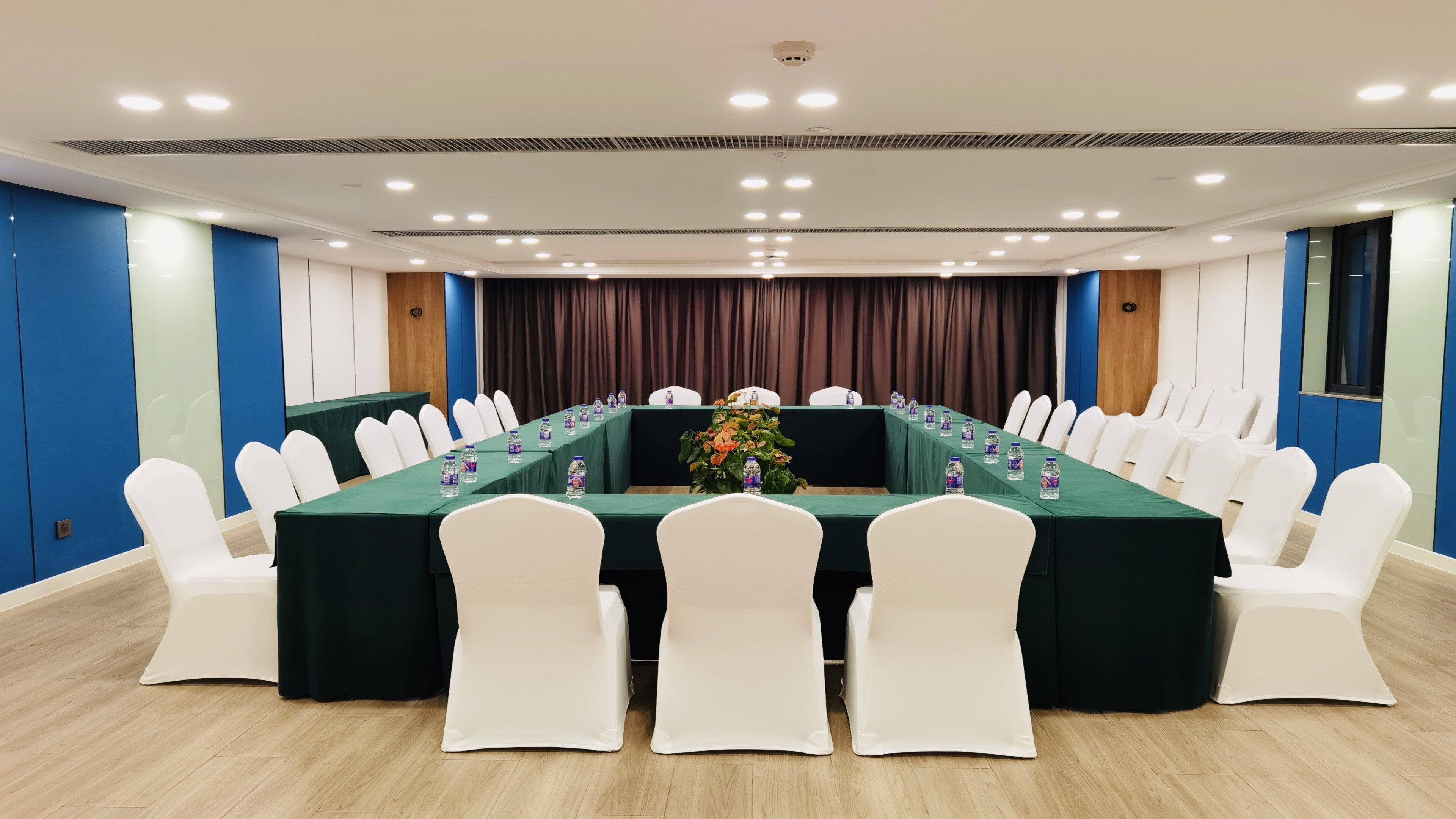 A conference room with a long table, white chairs, and water bottles.