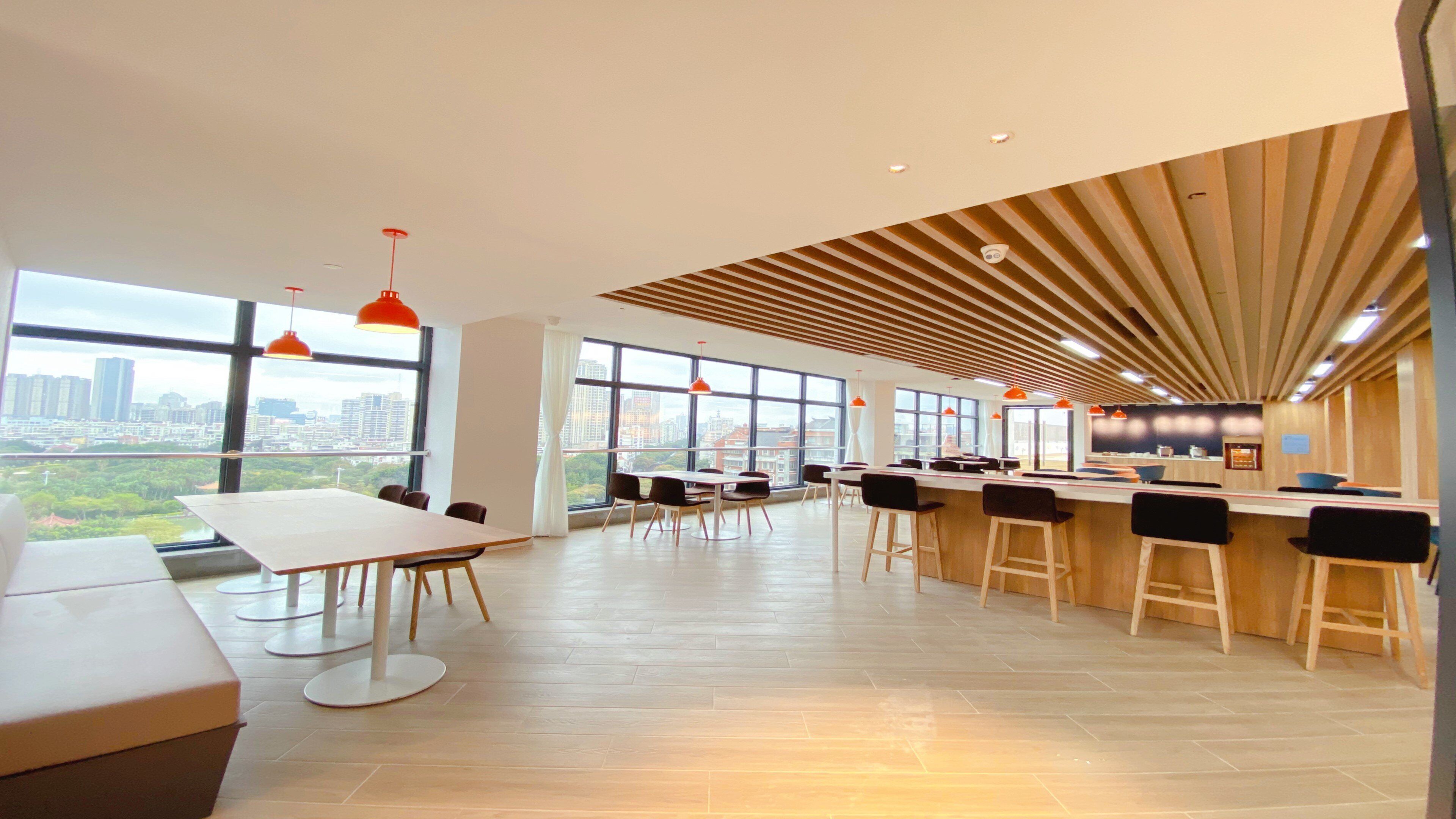 A modern office space with large windows, a bar area, and a view of the cityscape.