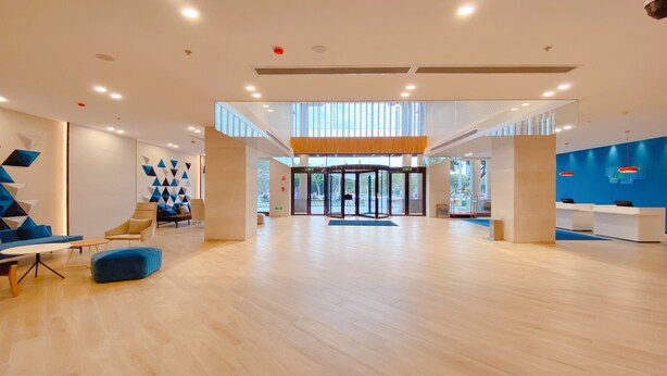 Un hall d’entrée spacieux au design moderne, doté d’une porte tournante centrale, de coins salon avec des canapés et d’un comptoir de réception.