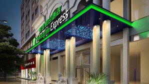 Un hôtel à la façade moderne, doté de grandes fenêtres et d’un panneau néon vert et bleu bien visible.