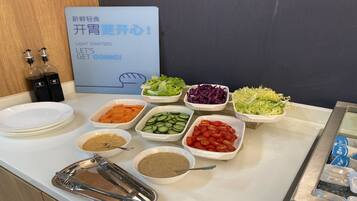 A buffet table with various food items and condiments.
