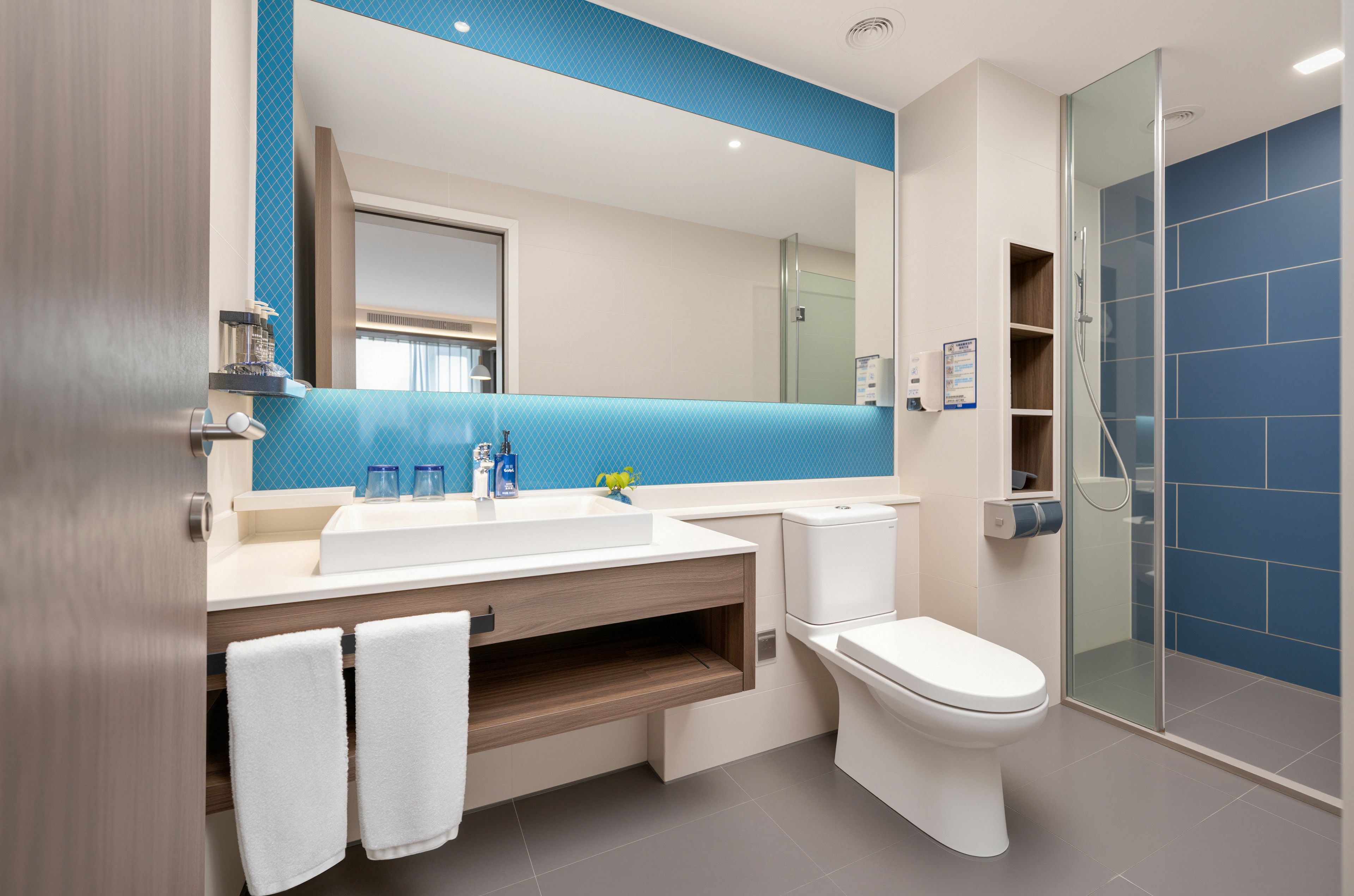 A modern bathroom with a large mirror, a sink, a toilet, and a shower area.