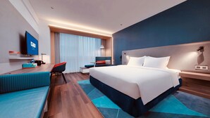 Une chambre d’hôtel moderne dotée d’un grand lit, d’un bureau avec une chaise, d’une télévision et d’une fenêtre avec des rideaux.