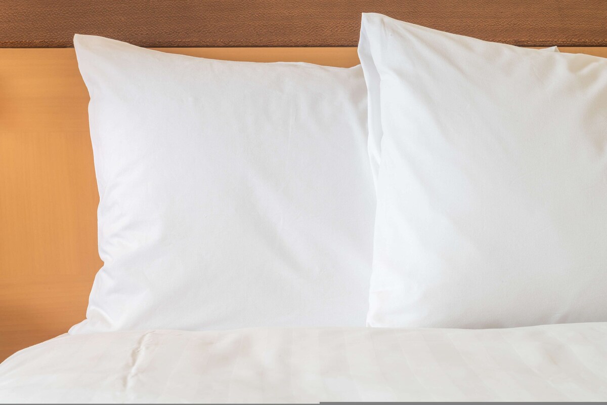 A bed with white bedding and a wooden headboard.