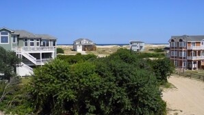 A coastal residential area with multiple houses, including a large house with a balcony and a smaller house with a garage. - Beautiful Carova beach house with ocean view, pool and hot tub! Pet Friendly! (Corolla)