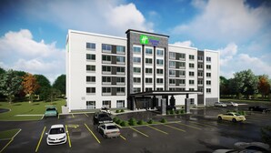 A modern hotel with a prominent green and white logo, multiple floors, and a parking lot with several cars. - Holiday Inn Express & Suites Aurora by IHG (Aurora)