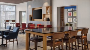 A modern dining area with a large table, red chairs, and a blackboard wall. - Holiday Inn Express & Suites Aurora by IHG (Aurora)