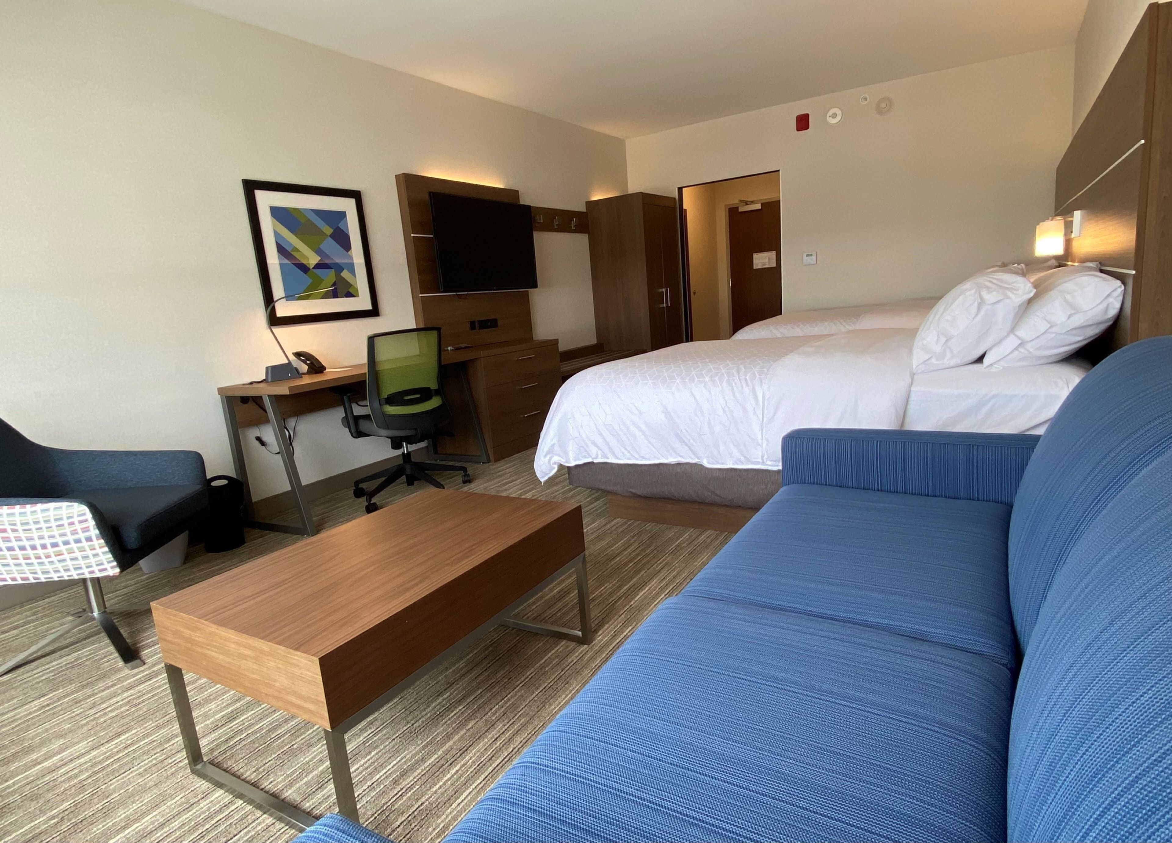 Une chambre d’hôtel comprenant un lit, un bureau, une chaise, un canapé et un téléviseur.
