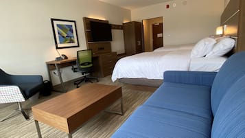 Une chambre d’hôtel comprenant un lit, un bureau, une chaise, un canapé et un téléviseur.