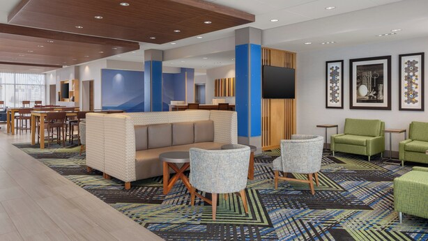 A modern hotel lobby with a seating area, a reception desk, and framed artwork on the walls. - Holiday Inn Express & Suites Aurora by IHG (Aurora)