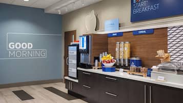 A breakfast area with a sign reading 'EXPRESS START BREAKFAST,' a wall with 'GOOD MORNING' text, and a counter with various food items and a coffee machine.
