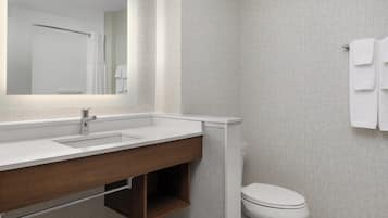 A modern bathroom with a white sink, mirror, and toilet.