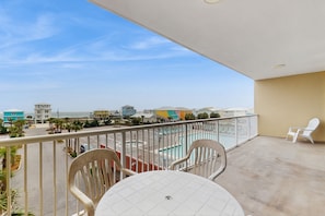 Enjoy the ocean view from this balcony with a table and chairs.