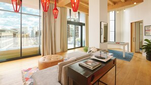 Un salon moderne doté d’une grande fenêtre, de poutres apparentes en bois au plafond et de luminaires rouges suspendus.