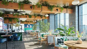 Un espace extérieur moderne, aménagé avec des tables et des chaises en bois, entouré de grandes fenêtres et agrémenté de plantes en pot.