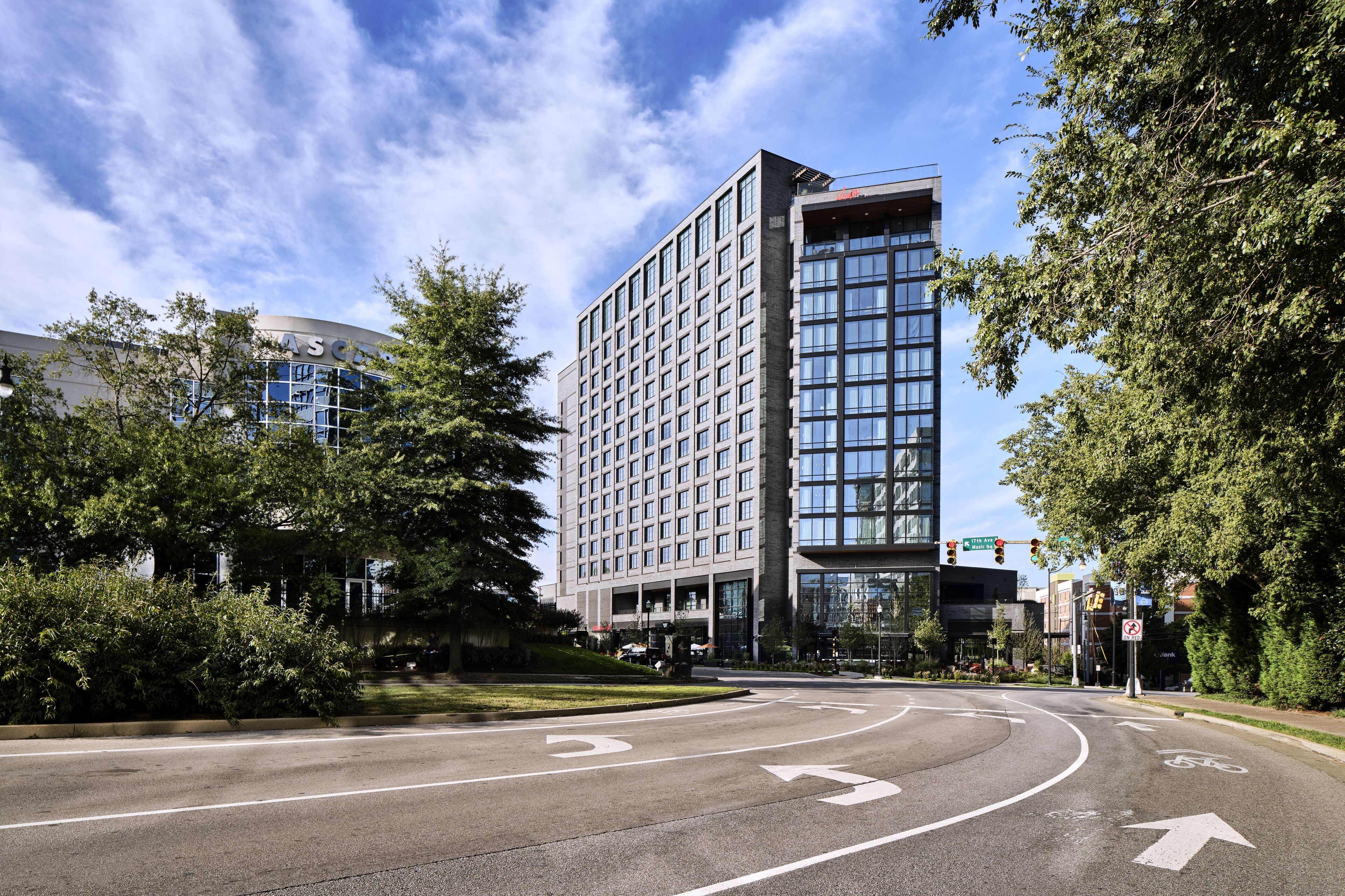 A modern hotel with a large glass facade, a central courtyard, and a roundabout intersection.