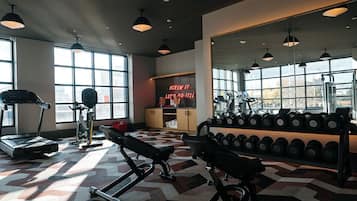 A gym with exercise equipment, large windows, and a motivational sign.