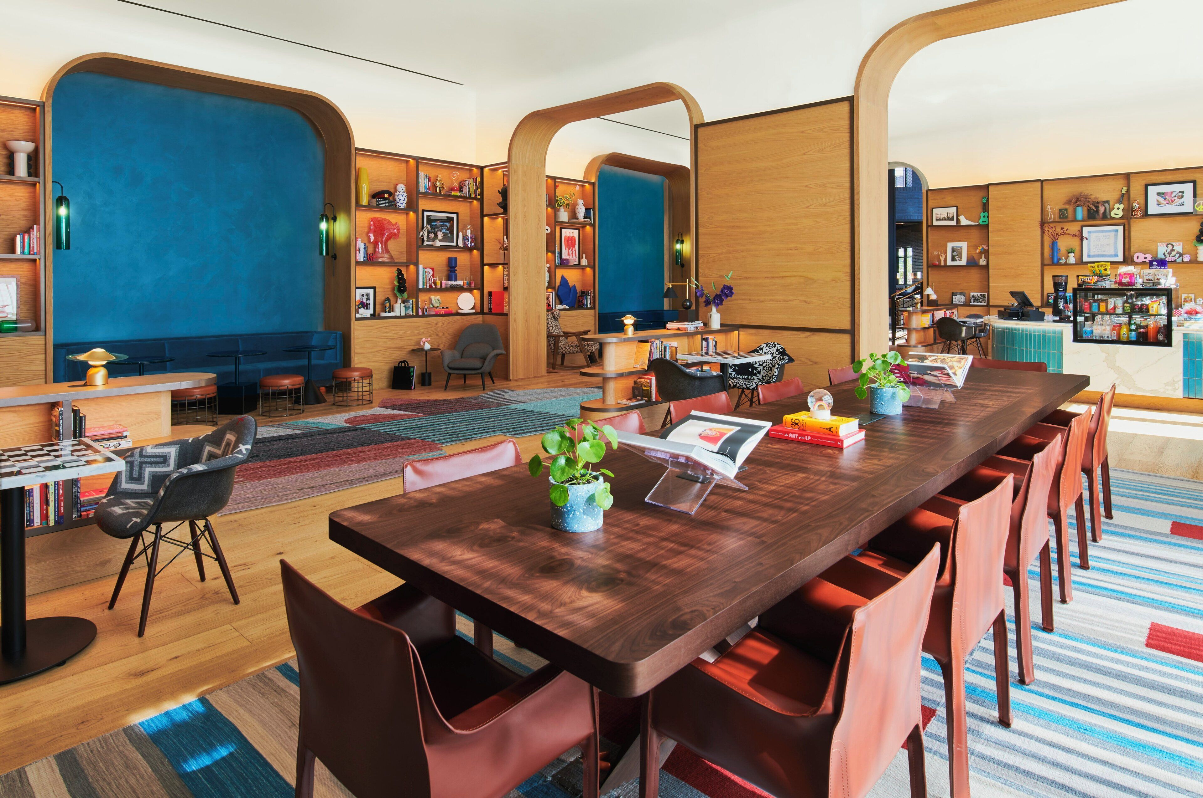 A modern conference room with a long wooden table, red chairs, and a blue accent wall.