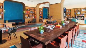 A modern conference room with a long wooden table, red chairs, and a blue accent wall.