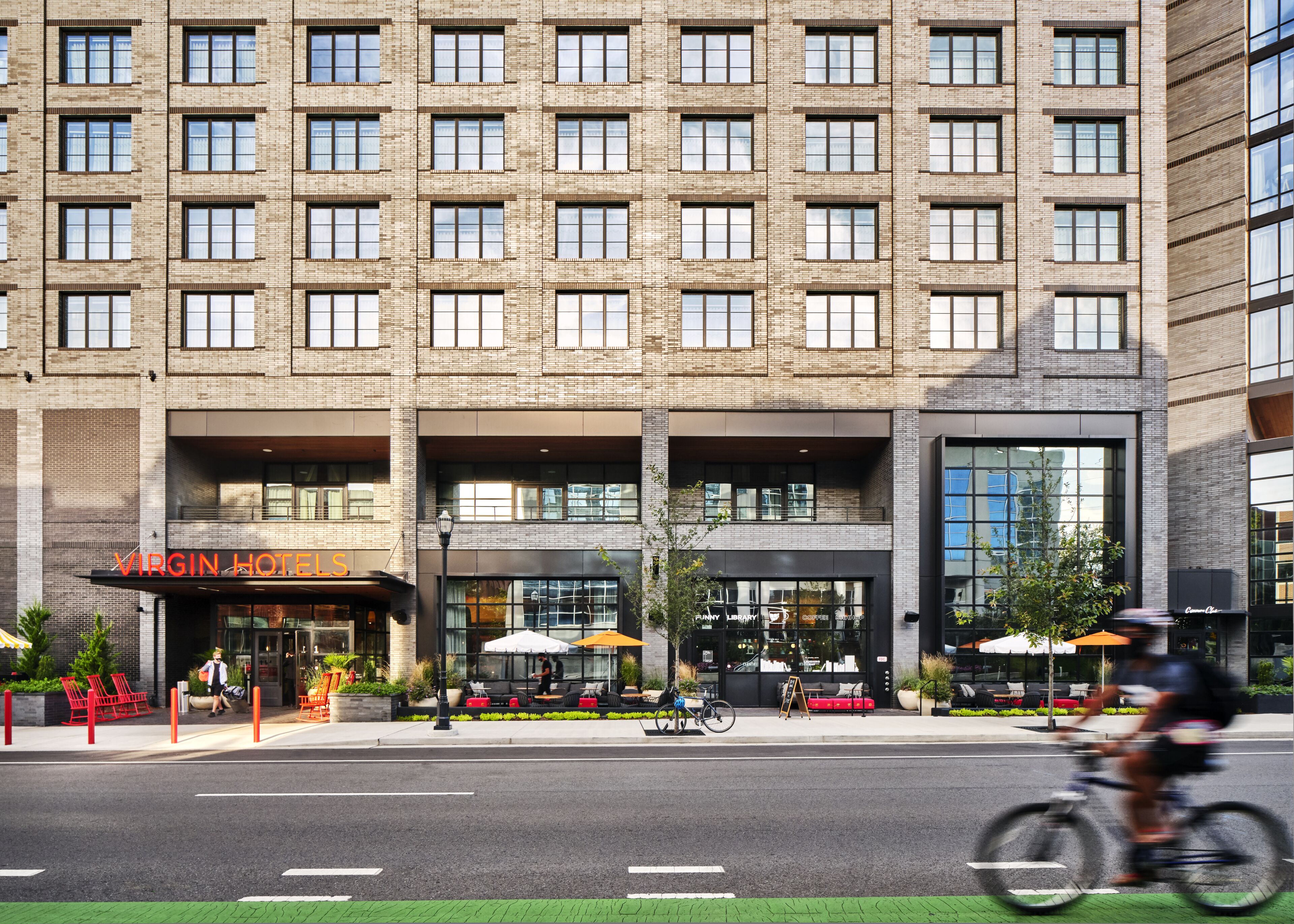 A modern building with a brick facade, a Virgin Hotel sign, and a library entrance.
