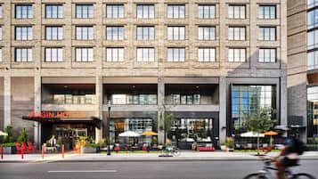 A modern building with a brick facade, a Virgin Hotel sign, and a library entrance.