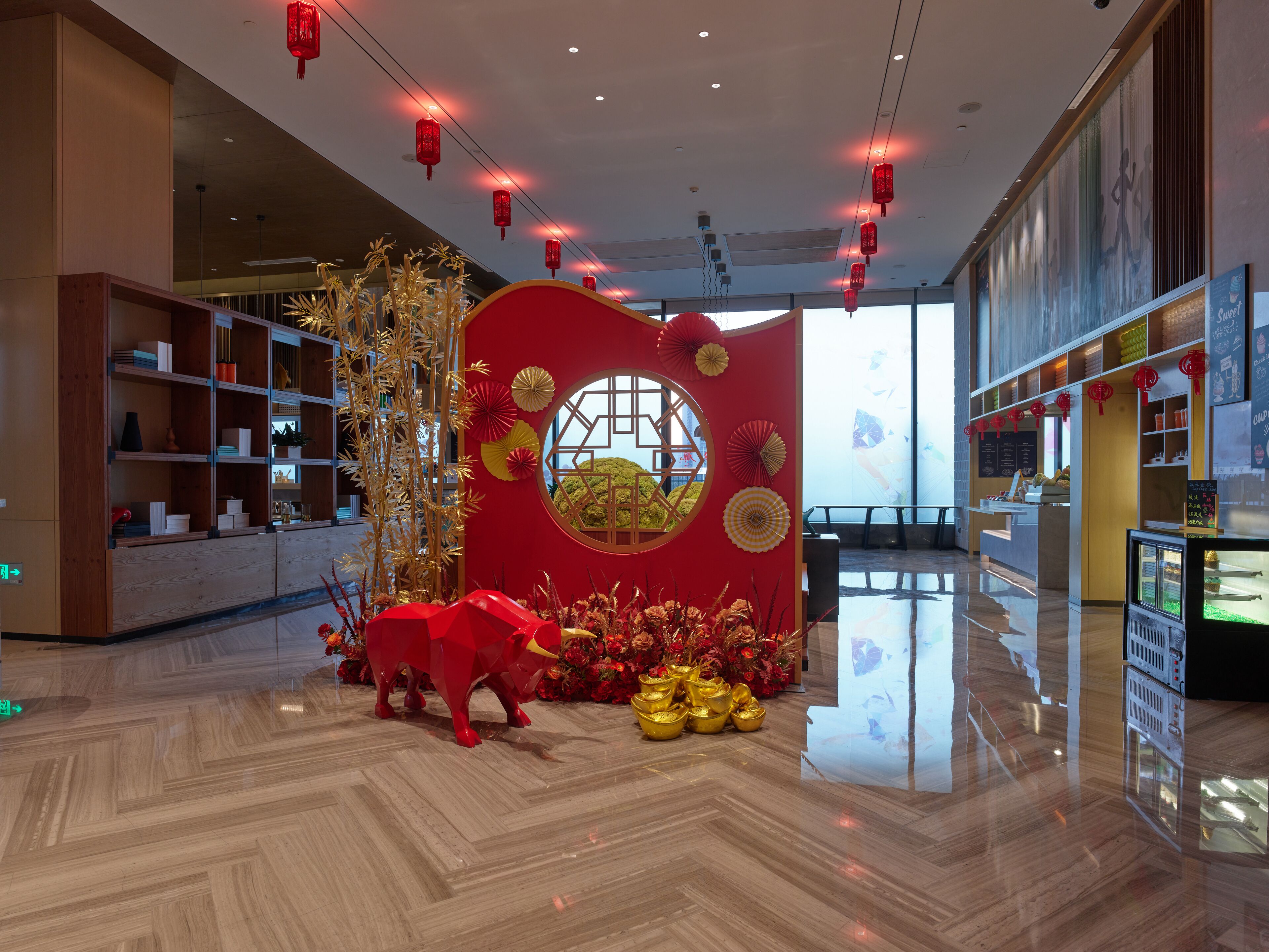 A modern interior with a reception desk, decorative paper lanterns, and a large window overlooking a green landscape.