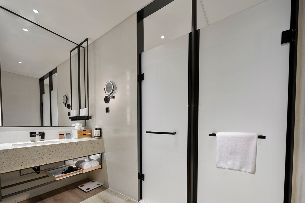 A modern bathroom with a large mirror, a towel rack, and a shower area.