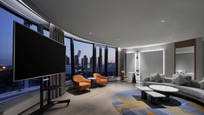 A modern hotel room with a large TV, comfortable seating, a small table, and a city view. - EVEN Hotel Nanjing Yangtze River by IHG (Nanjing)