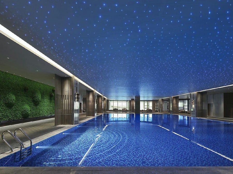 Ein Innenpool mit Sternenhimmel, grüner Wand und modernem Design.
