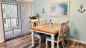 Een eethoek met een houten tafel, vier stoelen en een potplant.