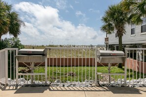 Outdoor barbecue area with grills and a fenced garden.