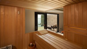 A sauna room with wooden benches and a view of a balcony with outdoor furniture.