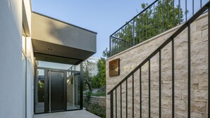 A modern building with a stone facade, a metal staircase, and a glass door entrance.