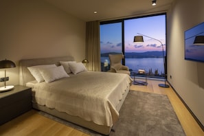Una camera da letto moderna con un letto grande, un comodino, una sedia e vista sull'acqua.