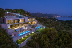 Una moderna casa a più piani con piscina, immersa nel verde e con vista sulla costa.