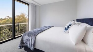 Una camera d'albergo moderna con un letto grande, vista sull'esterno e un balcone.