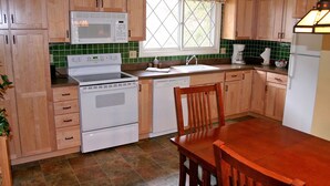 A kitchen with wooden cabinets, a white stove, a microwave, and a sink. - Fawn Valley Inn: 240 (Estes Park)