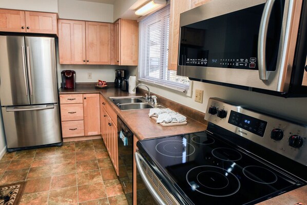 A modern kitchen with stainless steel appliances, wooden cabinets, and a tiled floor. - Fawn Valley Inn: 242 (Estes Park)