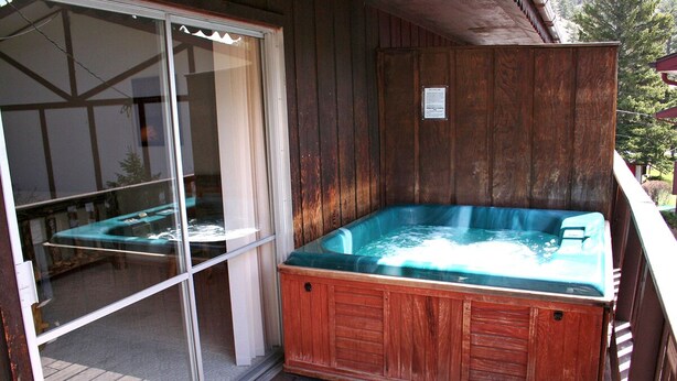 A wooden deck with a hot tub and a sliding glass door. - Fawn Valley Inn: 256 (Estes Park)