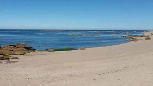 Kirkkaan taivaan ja tyynen veden ranta.
