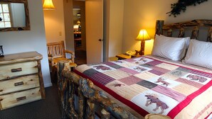 Una camera da letto con un letto con struttura in legno, una coperta con stampe di animali, un comodino con una lampada e un comò in legno.