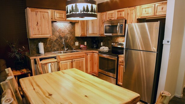 Una cucina con mobili in legno, un frigorifero in acciaio inox, un forno a microonde e un tavolo da pranzo.