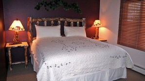A neatly made bed with a white quilt, two bedside lamps, and a wooden headboard. - Fawn Valley Inn: 280 (Estes Park)