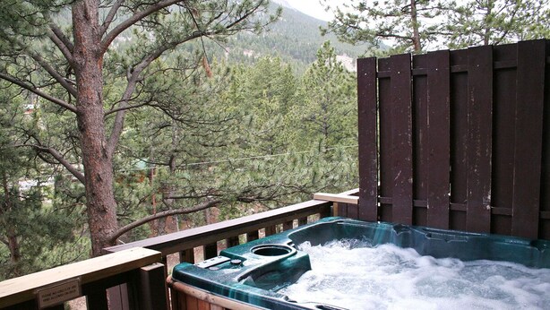 Un bain à remous avec une terrasse en bois et une vue sur les arbres et les montagnes.