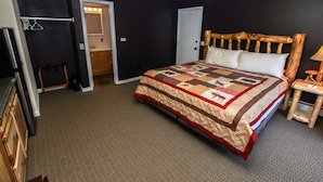 A bedroom with a large bed, a wooden headboard, a nightstand, and a ceiling fan. - Fawn Valley Inn: 293 (Estes Park)